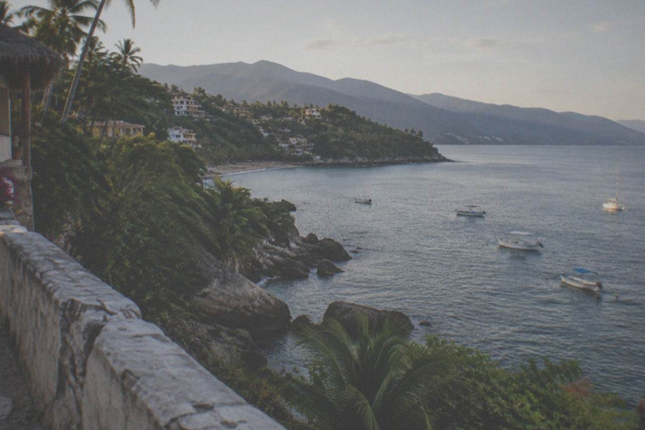Rocky headland overlooking a calm Pacific bay with small boats anchored offshore