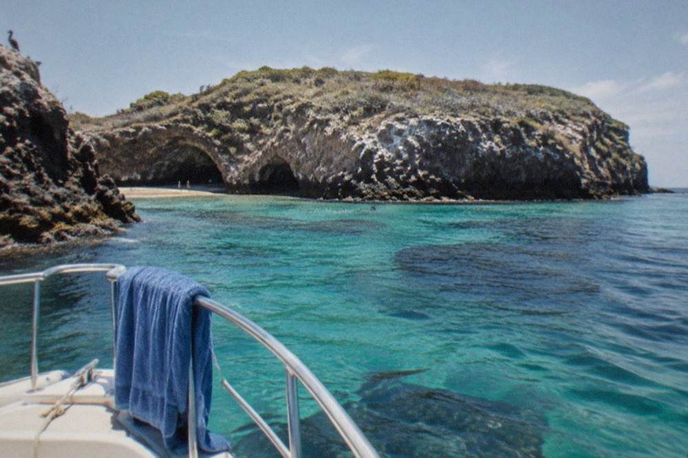 Small boat anchored near rocky islands with clear turquoise water
