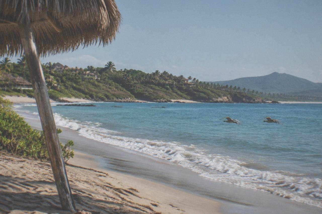 Sunny Puerto Vallarta coastline with calm blue water and green hills in the background