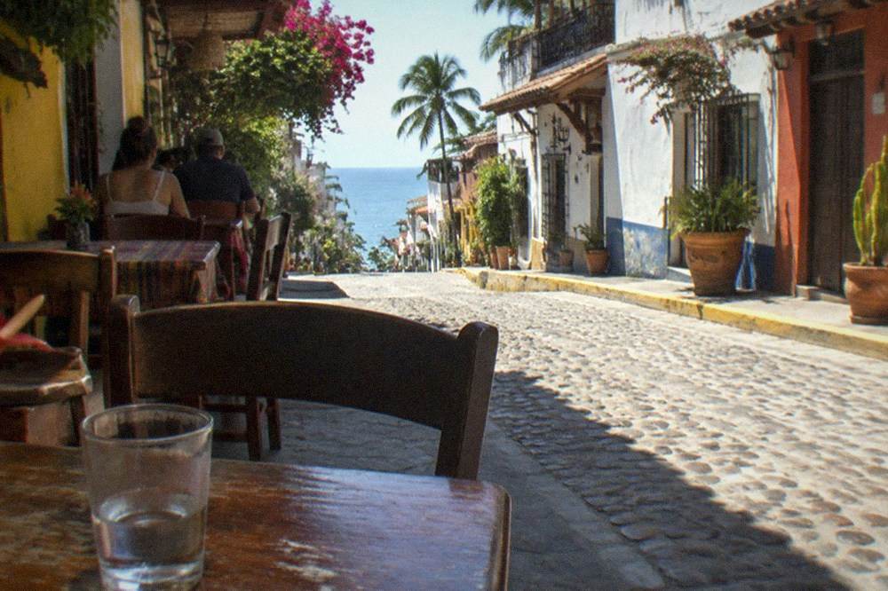 Colorful street in old town Puerto Vallarta with shops and restaurant tables along the sidewalk