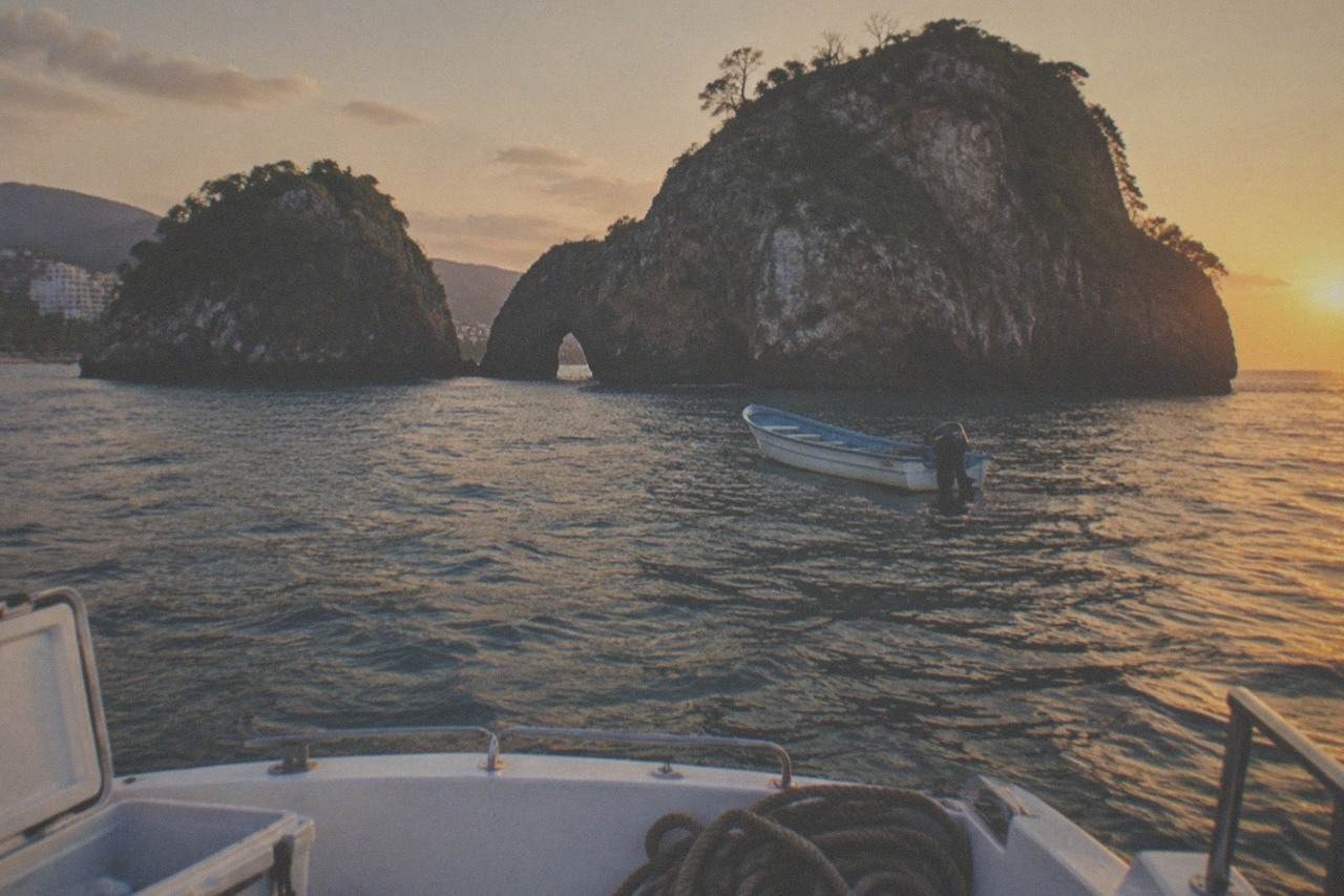 Small tour boat anchored in clear water near rocky islands off the Puerto Vallarta coast