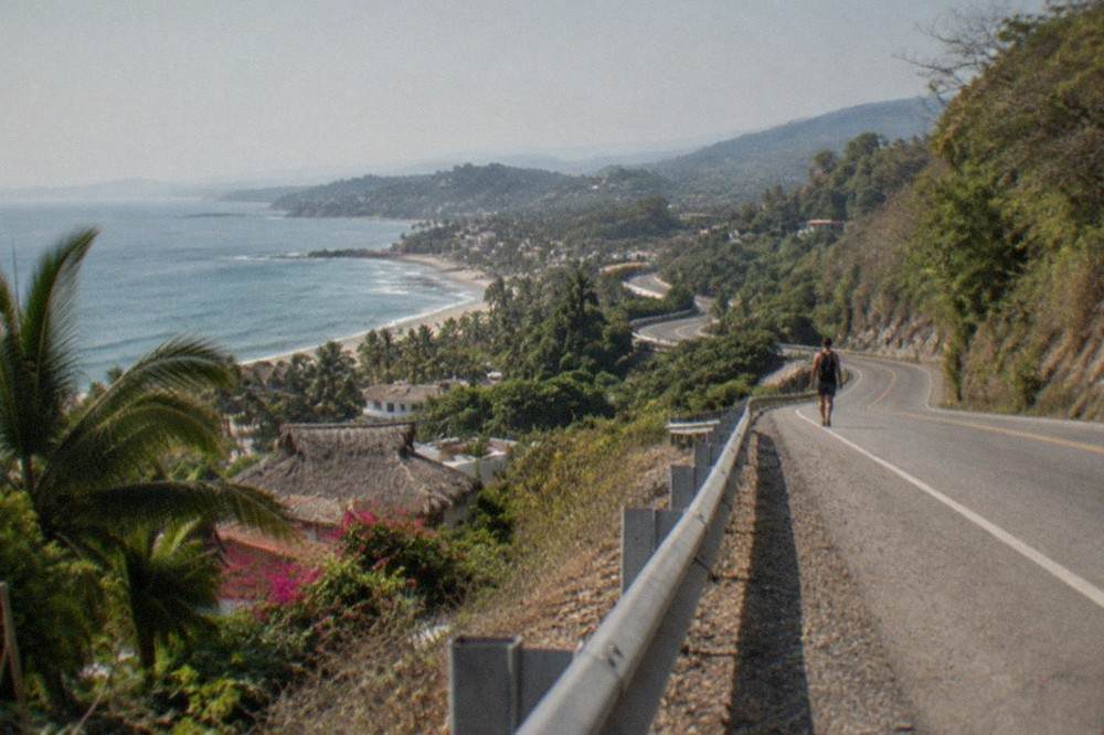 A coastal highway curving along green hills above the Pacific Ocean