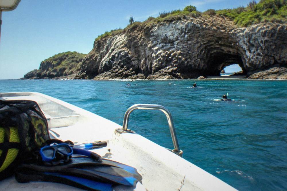 Snorkel masks, fins and a life vest stowed in a mesh bag on a sunny boat deck