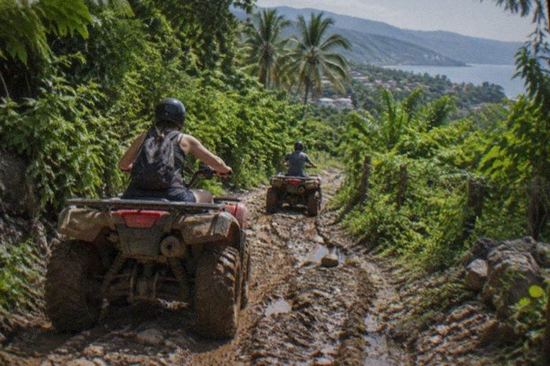 ATVs climb a jungle trail in the Sierra Madre foothills above Puerto Vallarta, green canopy pressing in on both sides of the track.
