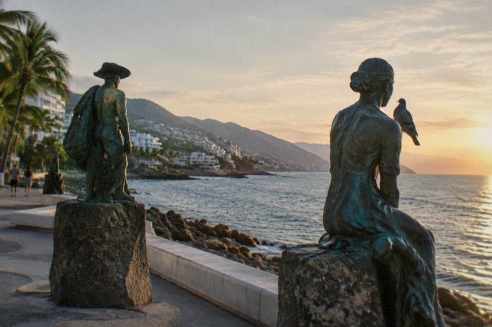 Bronze sculptures along a seaside boardwalk with the ocean in the background