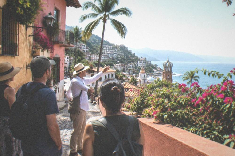 A group of people on a walking tour in a colorful Mexican town with a guide pointing