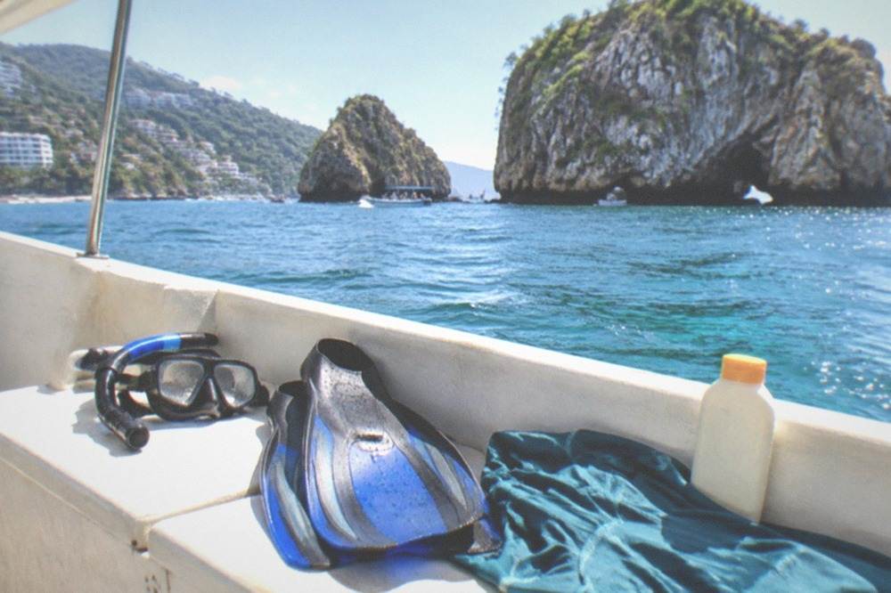 Snorkel mask and fins resting on a boat bench in bright sunlight