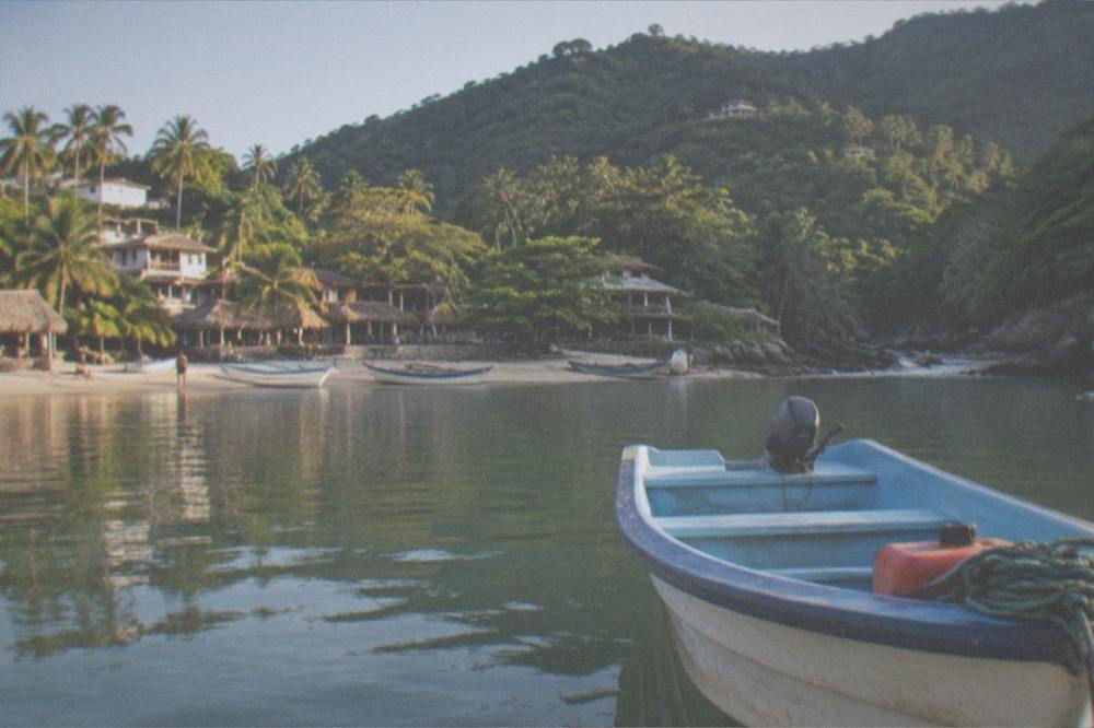 Small open panga boat anchored near rocky islands in calm morning water