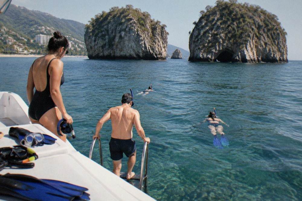 Group of snorkelers entering clear water from a small tour boat near rocky islands