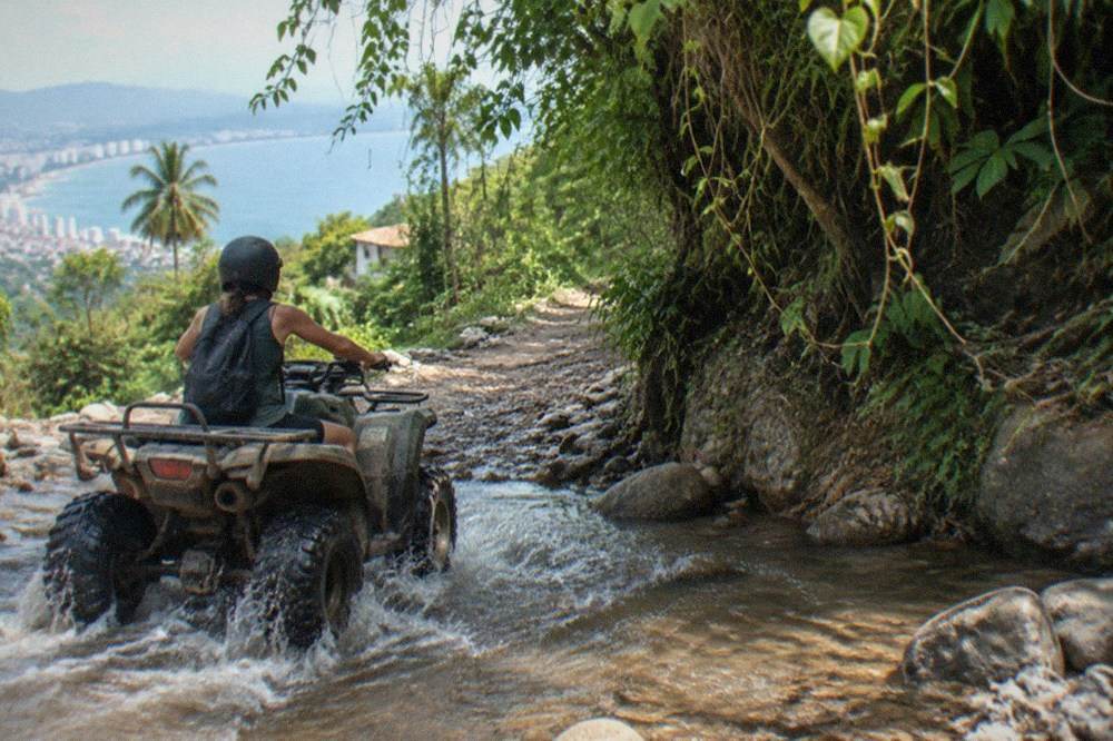 Single ATV crossing a jungle river crossing on a mountain trail
