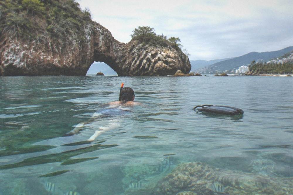 Snorkeler floating above rocky reef in clear blue water