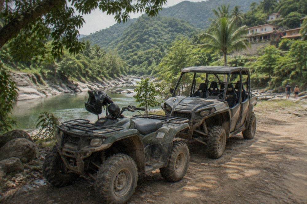 ATVs parked on a dirt road beside a jungle river