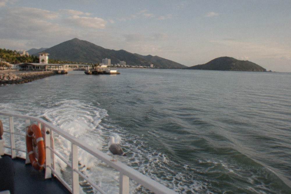 Tour boat cruising across calm open water toward green volcanic islands in Banderas Bay
