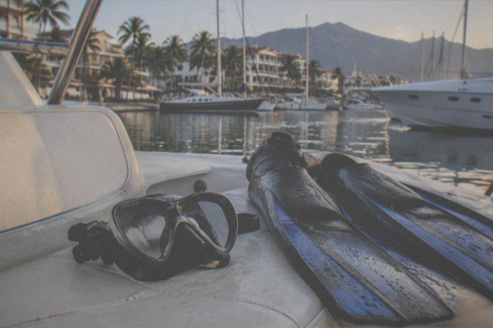 Mask and fins resting on a boat seat with ocean in background