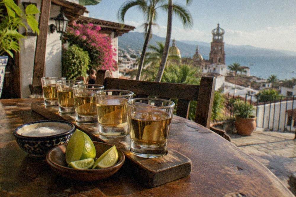 Glasses of amber tequila arranged on a wooden tasting table