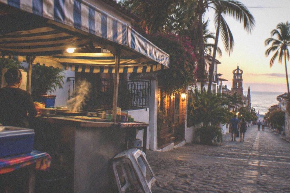 A street taco stand with colorful awnings on an evening in the Romantic Zone